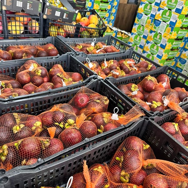 Crates filled with mesh bags of fresh mangosteens and mangoes at Linda's Tropical Fruits.